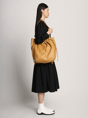 Image of model carrying Drawstring Tote in CARAMEL