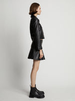 Side image of model wearing Leather Ruffle Mini Skirt in black