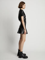 Side image of model wearing Faux Leather Ruffle Mini Dress in black