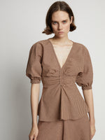Detail image of model wearing Gingham Long Sleeve Peplum Top in coral/black