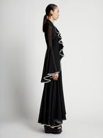Side image of model wearing Solid Mesh Ruffle Dress in black