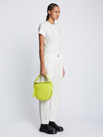 Image of model carrying Medium Baxter Leather Bag in LIME in hand