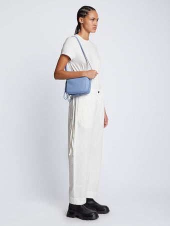 Side image of model carrying Watts Leather Camera Bag in PERIWINKLE