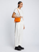 Side image of model carrying Watts Leather Camera Bag in TANGERINE