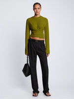 Front full length image of model wearing Ribbed Cotton Wrap Sweater in LEAF with straps tied around waist