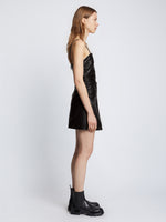 Side full length image of model wearing Faux Leather Ruched Mini Dress in BLACK