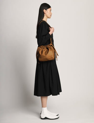 Side image of model carrying Drawstring Pouch in BARK