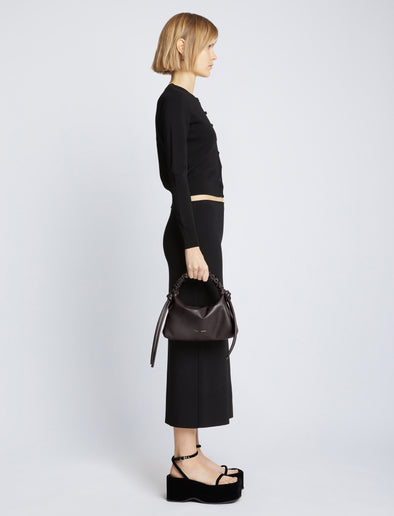 Image of model carrying Mini Drawstring Bag in BLACK