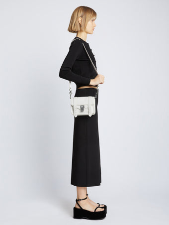 Image of model carrying Carved Python PS1 Mini Crossbody Bag in OPTIC WHITE