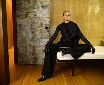 Person wearing a black outfit with gloves sitting on a bench.