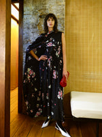 Image of model wearing Ysabelle Dress in Printed Silk Viscose in Black multi holding Silo Clutch in Shiny Calf in Red in an indoor setting