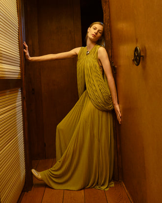 Image of model wearing Bari Dress in Gauzy Jersey in Olive in a room with wooden walls and floor