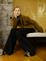 Image of model wearing Daria Jacket in Corduroy in Fatigue sitting on white chair