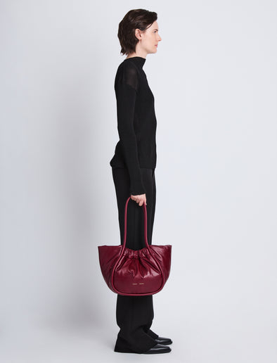 Image of model wearing Large Puffy Nappa Ruched Tote in GARNET