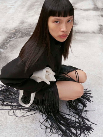 Cropped image of model squatting wearing the Sibyl Jacket in Stretch Nylon in black