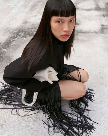 Cropped image of model squatting wearing the Sibyl Jacket in Stretch Nylon in black