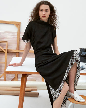 Cropped image of model sitting on a table in the Hallie Dress in Hammered Viscose in Black