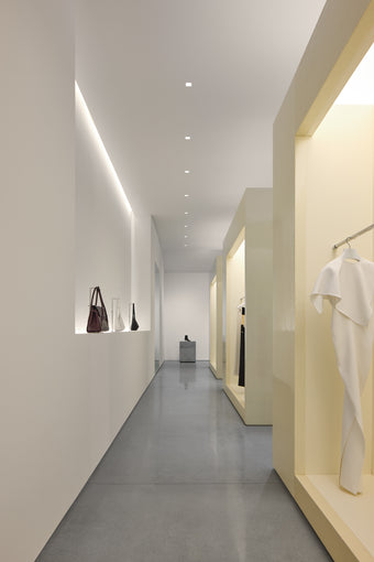 Interior of new Proenza Schouler flagship store at 153 Mercer Street. Image of large resin cubes containing clothing and handbags in a white room with concrete flooring.