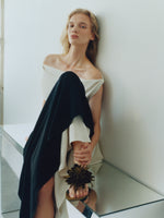 Proenza Schouler image of model sitting on mirrored table wearing the Daliah Dress in Satin Back Crepe in Black/Ecru with the Tee Thong Flower Sandals in Satin in Pstachio