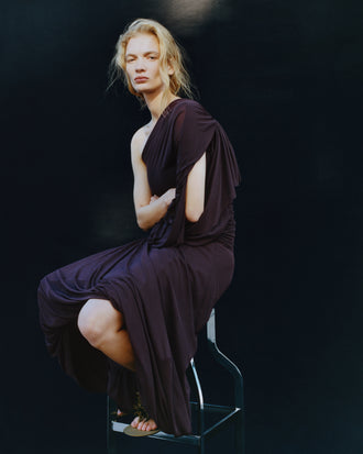 Proenza Schouler image of model sitting on a stool wearing Gabri Dress in Gauzy Pleated Jersey in Aubergine