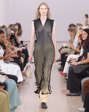 Model Walking Proenza Schouler SS24 Runway In Tauba Dress In Black Satin Ribbon, Roy Jean In Resin Nappa, Flip Shoulder Bag In Birch Nappa Leather, Bronco Chelsea Boots In Black Shiny Calf