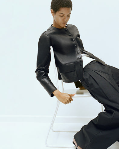 Proenza Schouler Editorial Image of model sitting on a chair wearing Robin Jacket in Leather in Black
