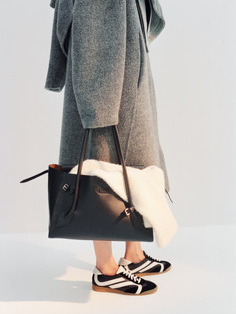 Cropped image of model wearing Albers Coat in Textured Double Face Wool in dark grey multi with Track Sneakers in black/white, carrying Tate Bag in black