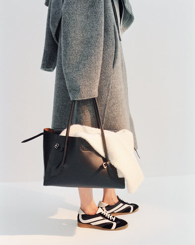 Cropped image of model wearing Albers Coat in Textured Double Face Wool in dark grey multi with Track Sneakers in black/white, carrying Tate Bag in black
