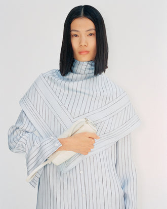 Cropped image of model wearing Hannah Dress in Stripe Silk Twill in pale blue multi, carrying Silo Bag in cream