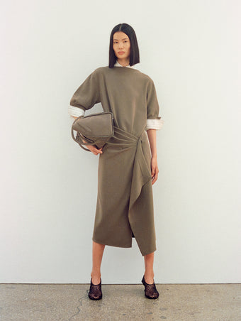 Image of model wearing Maisie Dress in Matte Double Crepe in wood with Tee Perforated Slingback Pumps in black, carrying Tate Bag in Nubuck Calf in slate