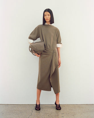 Image of model wearing Maisie Dress in Matte Double Crepe in wood with Tee Perforated Slingback Pumps in black, carrying Tate Bag in Nubuck Calf in slate