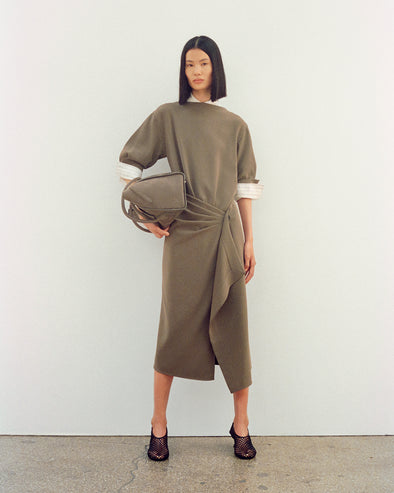 Image of model wearing Maisie Dress in Matte Double Crepe in wood with Tee Perforated Slingback Pumps in black, carrying Tate Bag in Nubuck Calf in slate