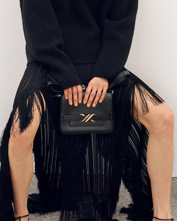 Cropped image of model wearing Alaina Skirt in Viscose Fringe Knit and Sandra Cashmere Sweater in black, carrying Box Bag in black