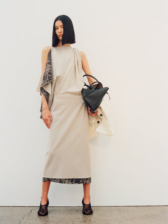 Image of model wearing Elena Dress in Wool Gabardine Suiting in taupe with Tee Perforated Slingback Pumps in black, carrying Tate Bag in black