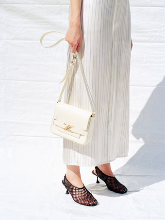 Cropped image of model wearing Hannah Dress in Stripe Silk Twill in ivory multi with Tee Perforated Slingback Pumps in black, carrying Box Bag in cream