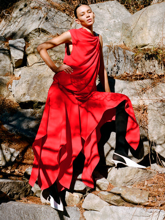 Image of model wearing Denise Dress in Light Matte Double Crepe in Red standing on rocky terrain