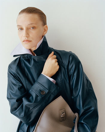 Model wearing Benedetta trench coat against a white wall 