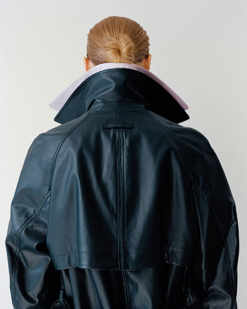 Model wearing Benedetta trench coat facing a white wall 