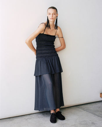 Model wearing the Michal dress in Melange Georgette leaning against a white wall