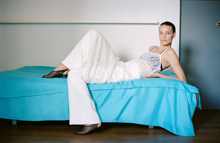 Model wearing Virginie Fringe Embroidery Dress in White laying on blue daybed
