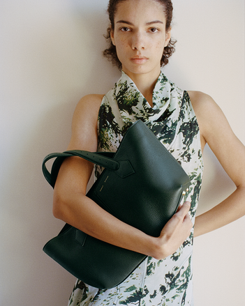 Model Elise Kouzou standing against white backdrop holding East West Chelsea tote