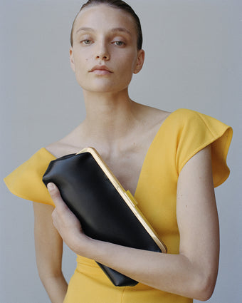 Detailed cropped image of model wearing the Mariam dress holding the Armory Clutch