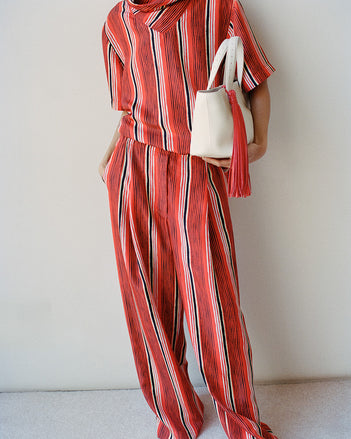 Model wearing Amira top and pant and East West tote against white wall 