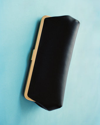 Image of black Nappa Armory Clutch against light blue background 