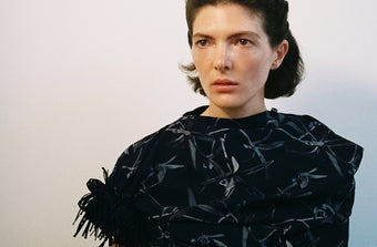 A wide portrait of a model in the Proenza Schouler FW26 Campaign wearing the Bodine dress in Ink multi