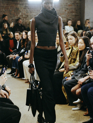 Cropped image of model walking Proenza Schouler FW24 Runway wearing Cruz Vest in Midweight Viscose Rib in grey with Avalon Skirt in Lacquered Viscose in black