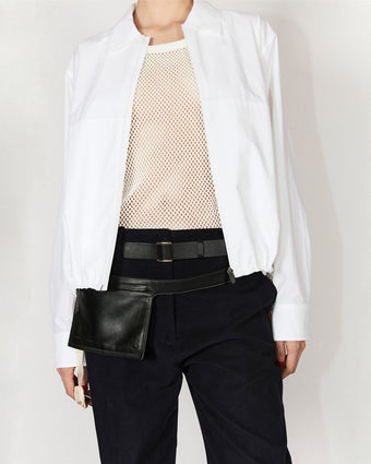 Cropped image of model wearing Emerson Jacket in Washed Cotton Poplin in white over Kiki Tank in Cotton Mesh in white, with Zip Belt Bag in black