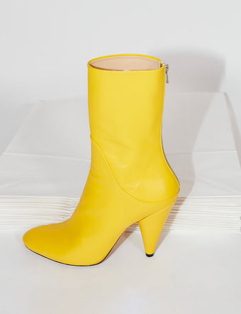 Yellow Cone Ankle Boots on stack of white paper bags