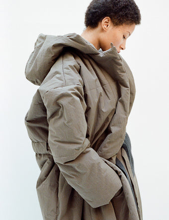 Side image of model in Technical Suiting Wrap Coat in wood