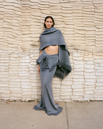 Model wearing Toni Dress in Textured Knits and Shawl in Textured Knits in ash grey, standing against brick wall